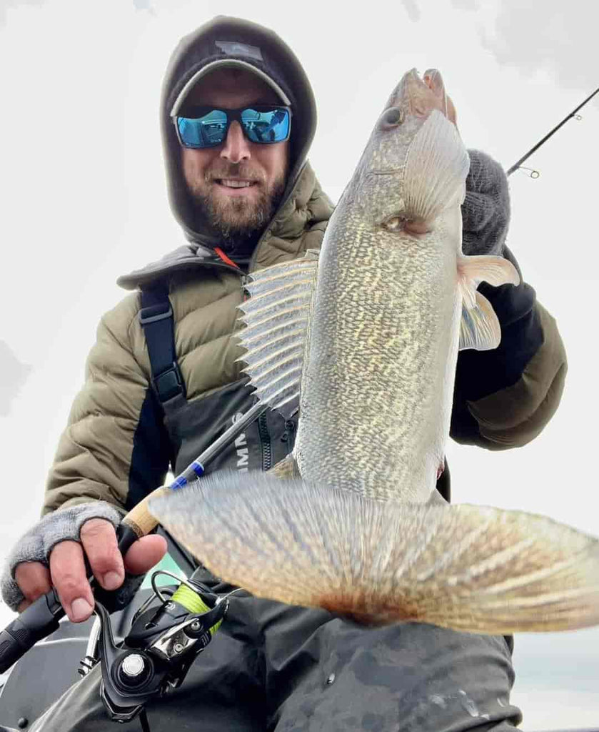 Angler in a boat proudly holding up a large fish caught with KADE Outdoors rod
